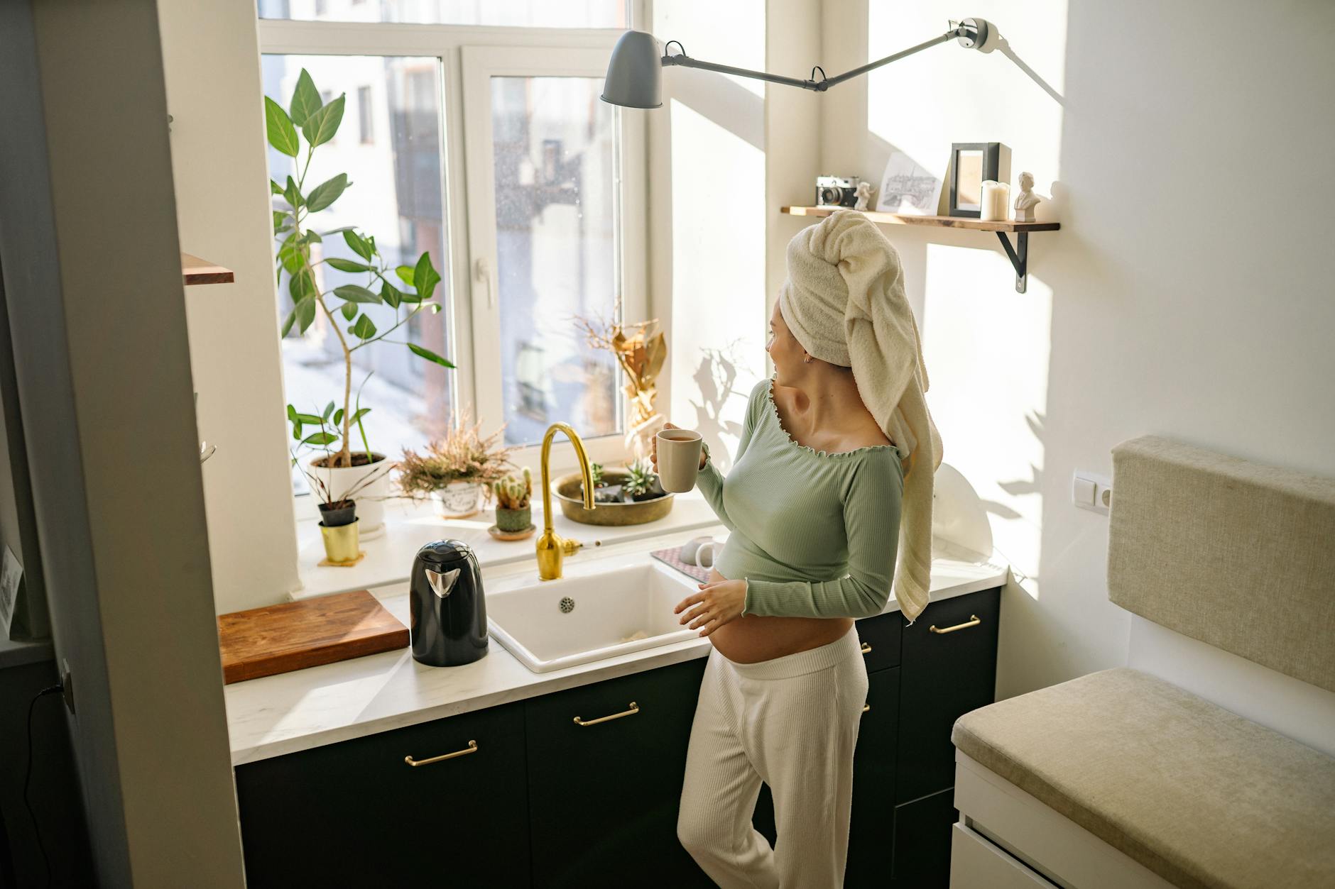 Femme enceinte s'hydrate le matin dans sa cuisine